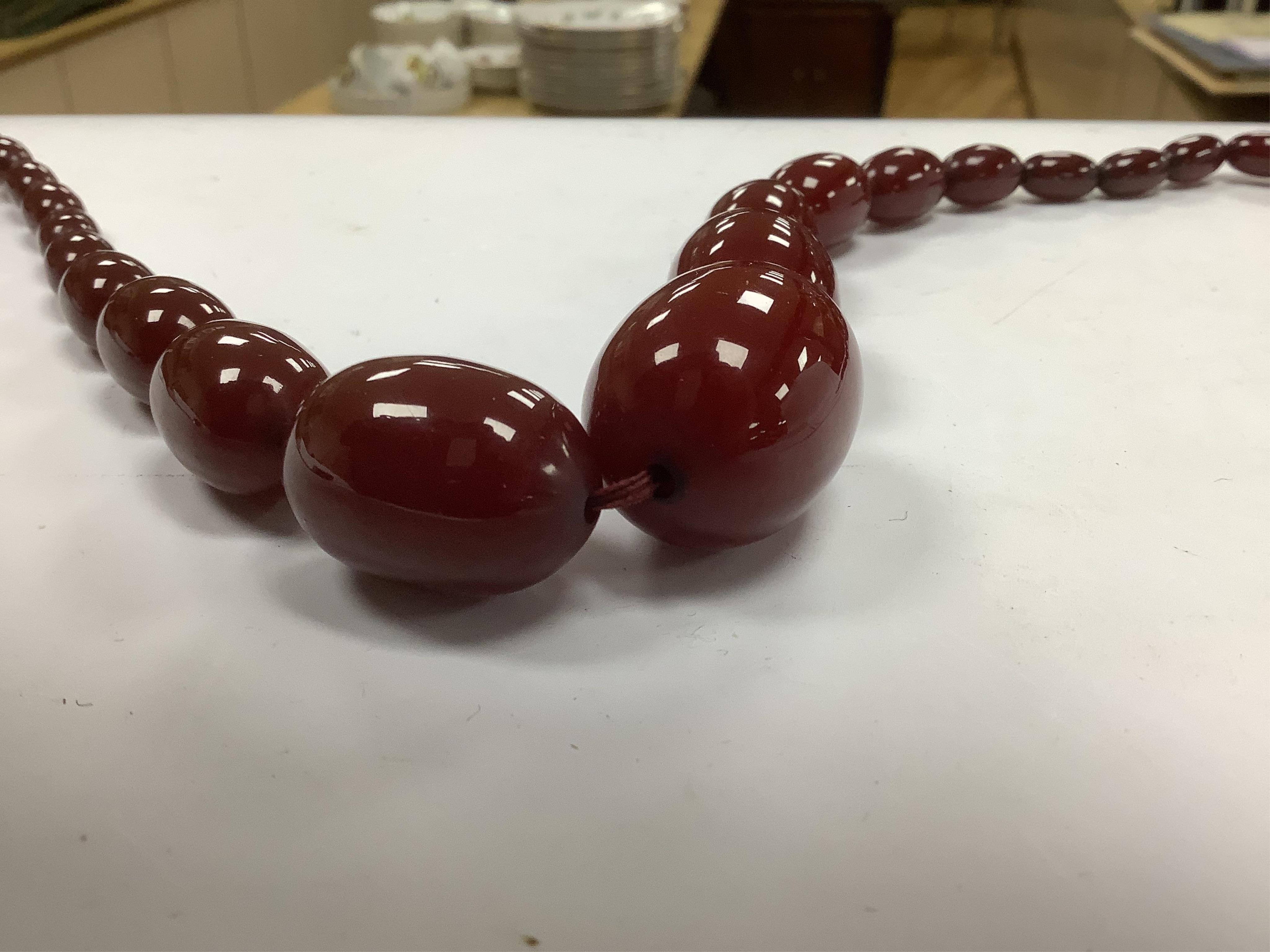 A graduated simulated cherry amber bead necklace, 43cm, gross weight 54 grams and two other necklaces including malachite. Condition - fair to good